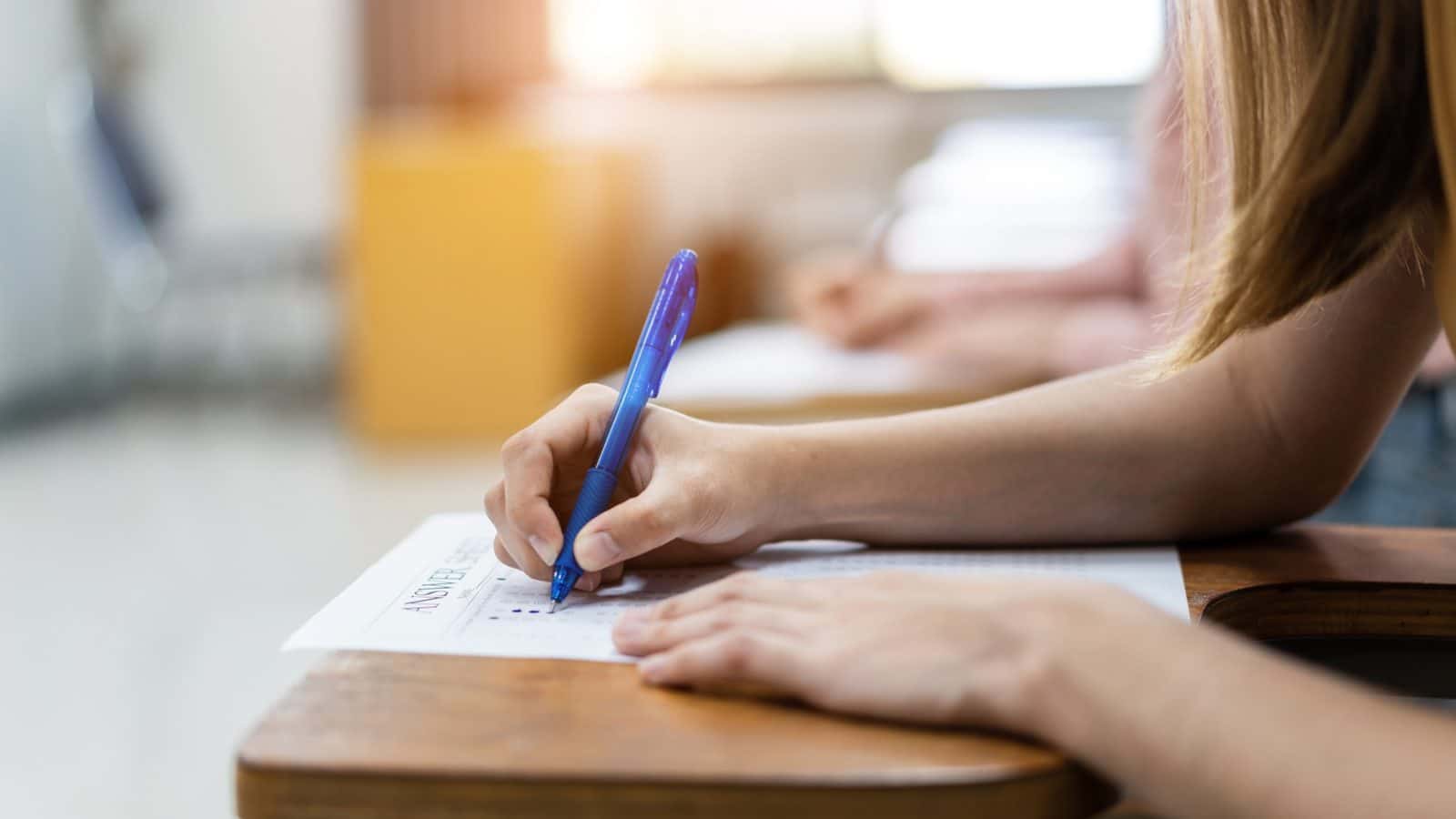 Student schrijft geconcentreerd aan een tafel, beeld bij Hoe kan ik groeien in geloof